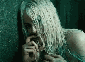 a woman with long white hair is holding her hand to her mouth .
