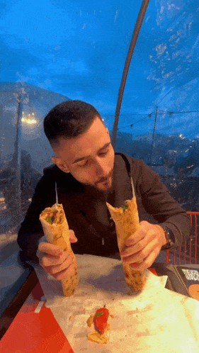 a man is sitting at a table eating a sandwich