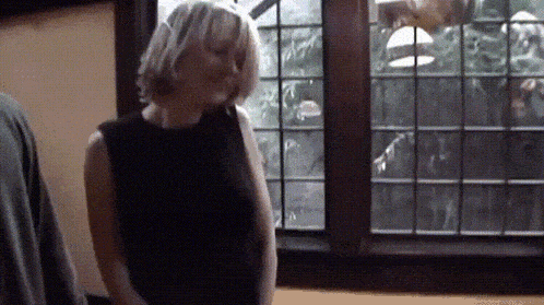 a woman in a black dress is standing in front of a window