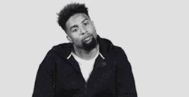 a black and white photo of a man with a beard wearing a black hoodie .