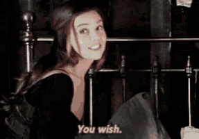 a woman in a black dress is talking to a man in a dark room and says `` you wish '' .