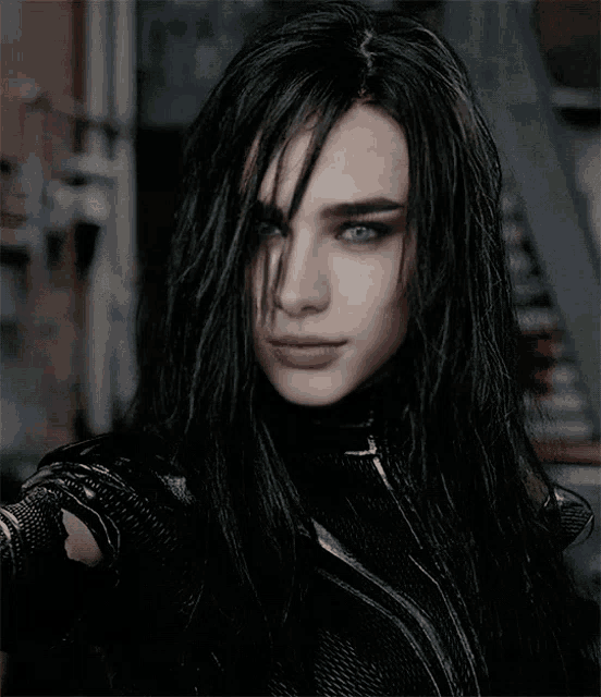 a woman with long black hair and blue eyes is wearing a black outfit