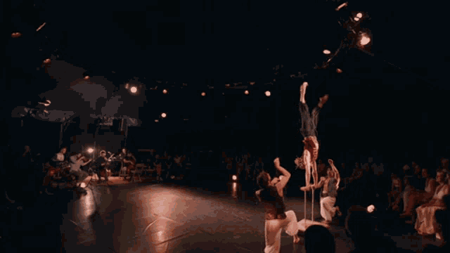 a group of people are performing acrobatics on a stage in front of a crowd
