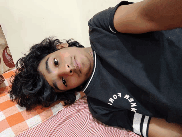 a young man is laying on a bed wearing a black shirt that says " яо7я3иv "