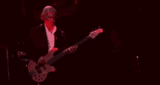 a man is playing a red guitar on a stage