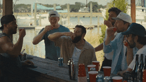 a group of men sitting around a table drinking