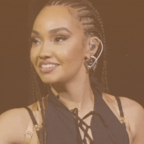 a woman wearing braids and heart shaped earrings looks surprised