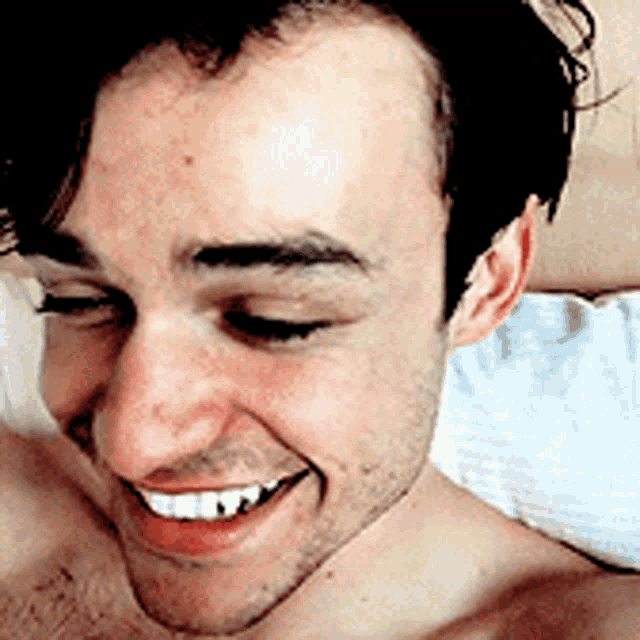 a shirtless man is smiling with his eyes closed and his mouth open