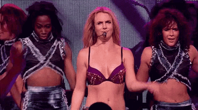 a woman in a bra is standing on a stage with a microphone in her hand .