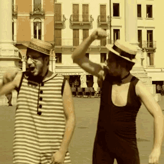 a man in a straw hat stands next to another man in a bathing suit