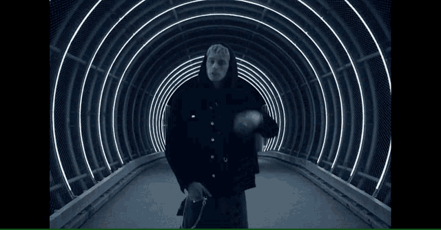 a man in a kilt is standing in a tunnel with lights behind him
