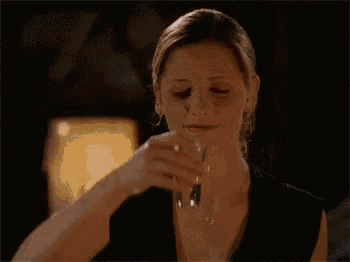 a woman in a black dress is drinking from a glass .
