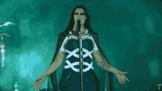 a woman singing into a microphone with the letter t visible in the background