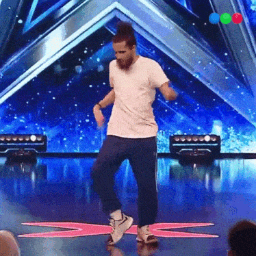 a man in a white shirt and blue pants is dancing on stage