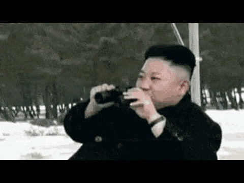 a man is drinking from a bottle while looking through binoculars .