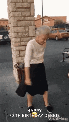 an elderly woman is dancing in a parking lot .