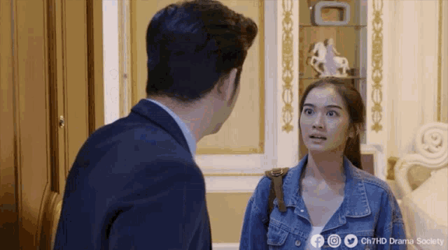 a man in a suit and a woman in a denim jacket are standing next to each other in a room ..