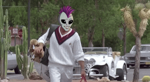 a man wearing a mask is walking a dog on a leash in front of a stop sign