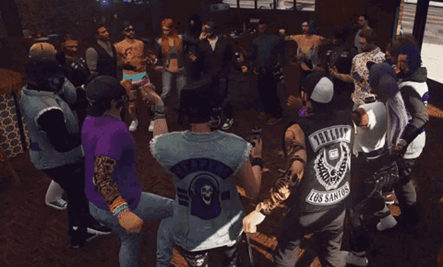 a group of people are dancing in a room and one of them is wearing a shirt that says tattooed los santos on it