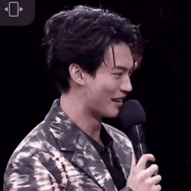 a man in a camouflage jacket is holding a microphone .