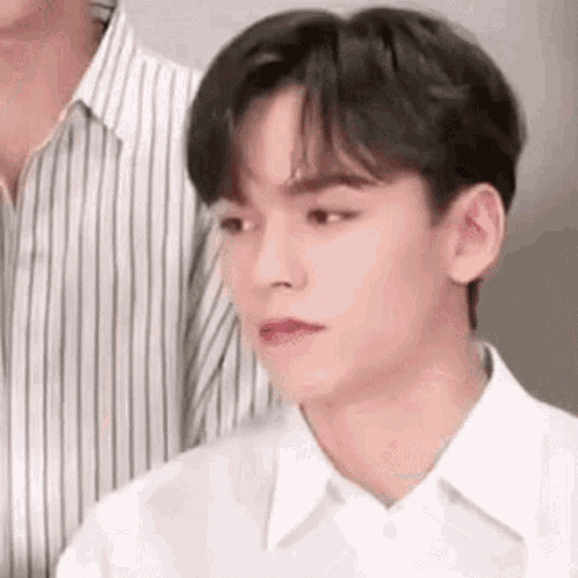 a close up of a young man wearing a white shirt and a striped shirt .