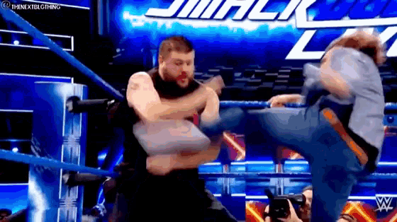a wrestler is kicking another wrestler in the face during a match .