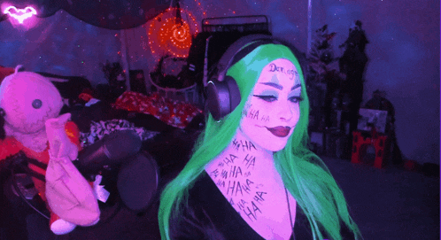 a woman with green hair is wearing headphones and has ha written on her face and neck