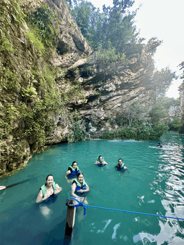 a group of people in life jackets are swimming in a river