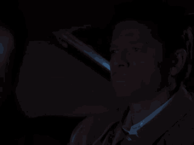 a close up of a man 's face in the dark with a shadow on his face