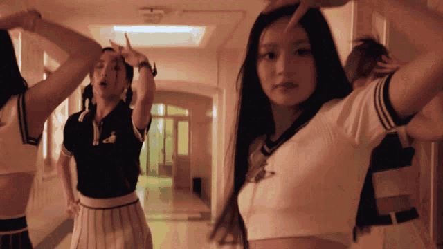 a group of girls are dancing in a hallway and one of them is wearing a crop top