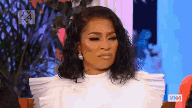 a woman is making a funny face while wearing a white shirt and earrings .
