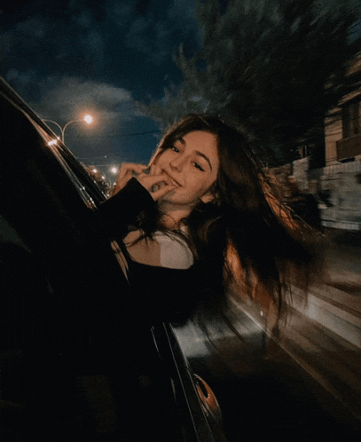 a woman is sticking her tongue out of a car window at night
