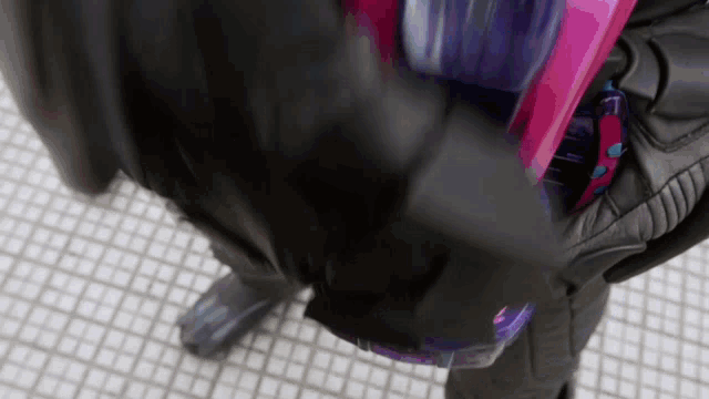 a person is holding a pink and purple object in their hand .