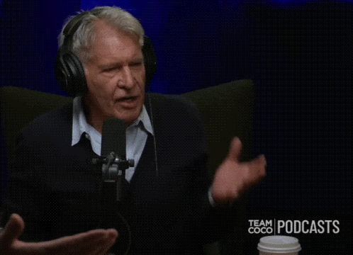 a man wearing headphones is sitting in front of a microphone and saying " shut the "