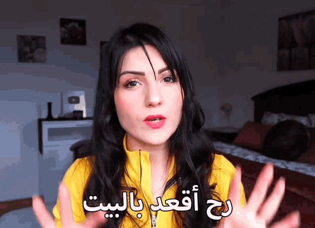 a woman wearing a yellow jacket is talking in arabic