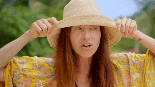 a woman wearing a straw hat is making a face
