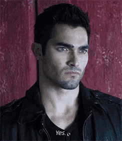 a man with a beard is wearing a black jacket and a black shirt .