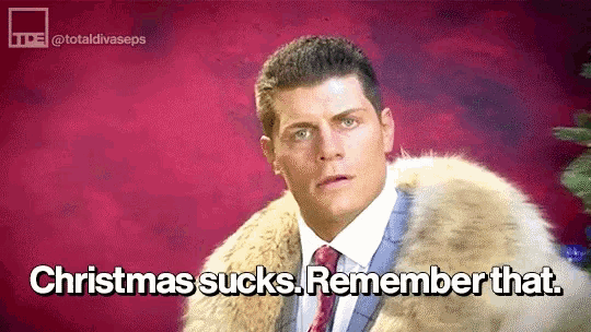 a man in a suit and tie is wearing a fur coat and says christmas sucks . remember that .