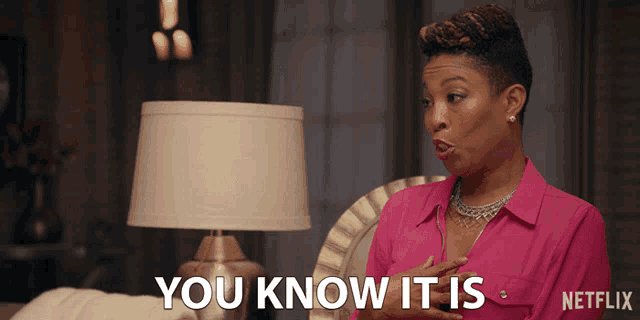 a woman in a pink shirt says " you know it is " in front of a lamp