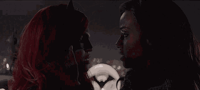 two women are looking at each other with one wearing a batman mask .