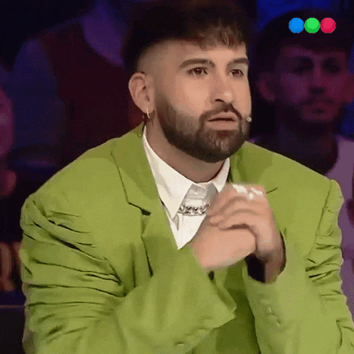 a man with a beard is wearing a green jacket and tie