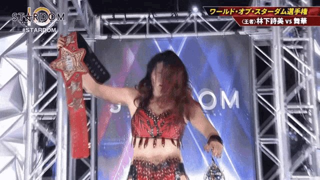 a woman in a red top is holding a belt with the word stardom on it