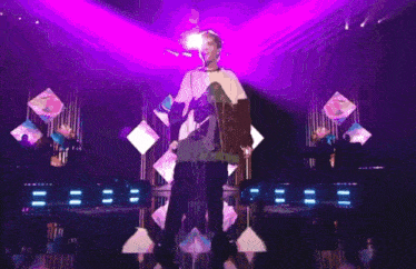 a man is standing on a stage in front of a purple light