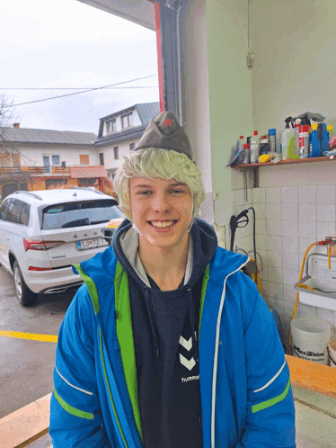 a young man wearing a blue jacket and a hummel sweatshirt smiles for the camera