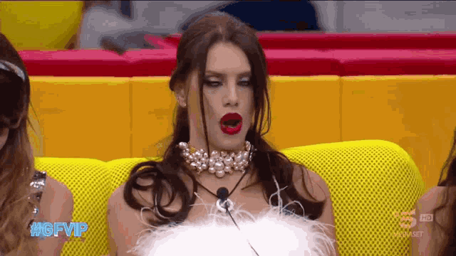 a woman sitting on a yellow couch with the hashtag #gfvip on the screen