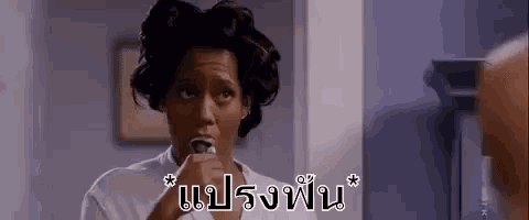 a woman is brushing her teeth in front of a mirror while looking at herself in the mirror .