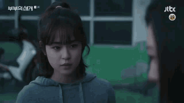 a woman in a gray hoodie is talking to another woman in a foreign language