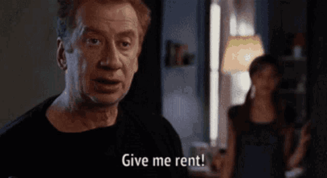 a man in a black shirt says give me rent in front of a woman