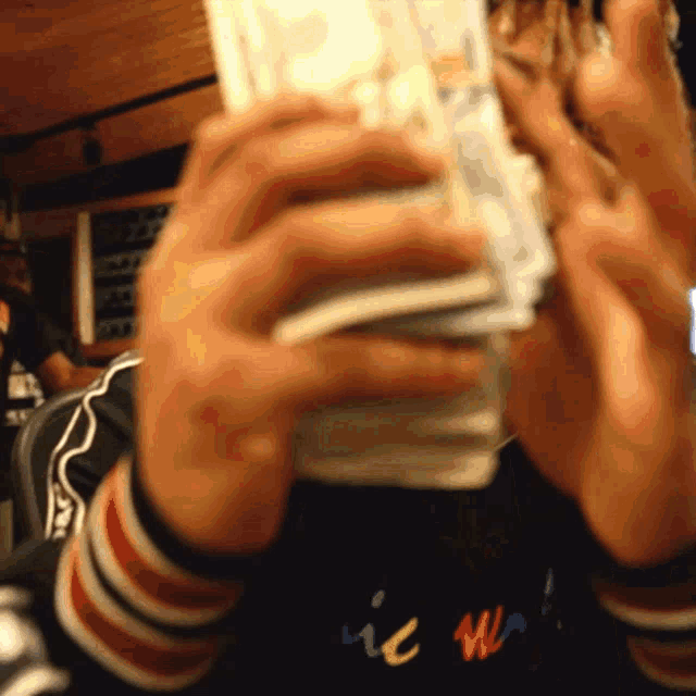 a person holding a stack of money in front of their face with the word ic written on their sleeve
