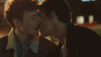 a couple of men are kissing each other in a dark room